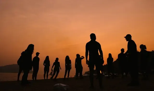 A group of people's silhouettes in front of a sunrise